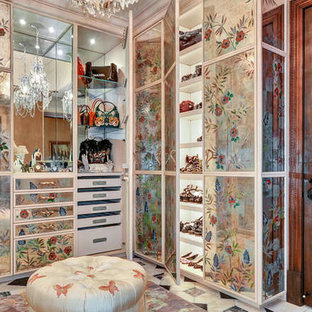 Immagine di un'ampia cabina armadio unisex mediterranea con ante di vetro, ante con finitura invecchiata, moquette e pavimento beige