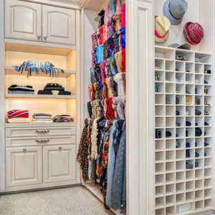 Idee per un'ampia cabina armadio unisex mediterranea con ante con bugna sagomata, ante con finitura invecchiata, moquette e pavimento beige