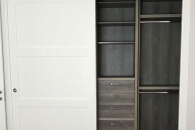 Reach-in closet - small modern gender-neutral reach-in closet idea in Miami with flat-panel cabinets and white cabinets