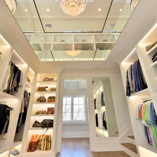 Idee per un'ampia cabina armadio unisex chic con nessun'anta, ante bianche e pavimento in legno massello medio