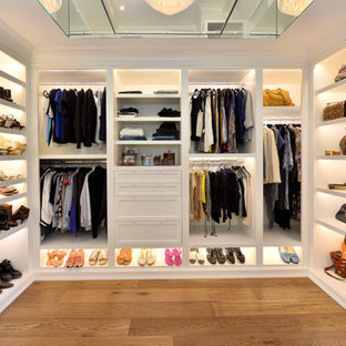 Immagine di una grande cabina armadio unisex chic con nessun'anta, ante bianche, pavimento in legno massello medio e pavimento marrone