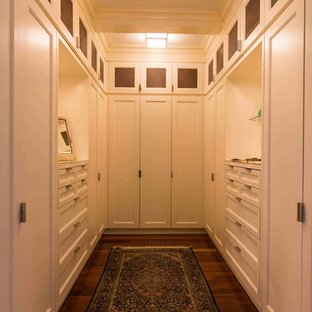 Foto di un'ampia cabina armadio unisex tradizionale con ante in stile shaker, ante bianche, pavimento in legno massello medio e pavimento marrone