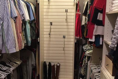 Diseño de armario vestidor unisex clásico renovado de tamaño medio con armarios con paneles lisos, puertas de armario blancas y suelo de madera oscura