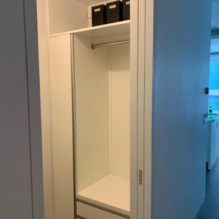 Esempio di una piccola cabina armadio industriale con ante lisce, ante bianche, pavimento in cemento e pavimento grigio