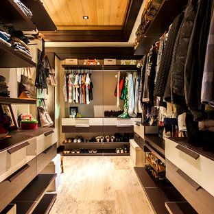 Example of a mid-sized island style gender-neutral beige floor and porcelain tile walk-in closet design in Hawaii with flat-panel cabinets and dark wood cabinets