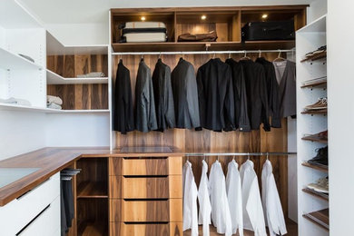 Diseño de armario vestidor unisex minimalista grande con armarios con paneles lisos, puertas de armario de madera oscura, suelo de mármol y suelo blanco
