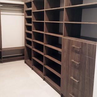 Modelo de armario vestidor unisex, minimalista, grande, con armarios con paneles lisos, puertas de armario de madera en tonos medios, suelo de baldosas de cerámica y suelo blanco