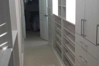 Small gender-neutral carpeted walk-in closet photo in Toronto with flat-panel cabinets and white cabinets