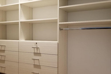 Imagen de armario vestidor unisex y abovedado minimalista extra grande con armarios con paneles lisos, puertas de armario de madera clara, suelo de madera clara y suelo beige