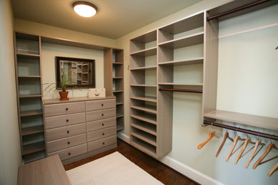 Diseño de armario vestidor unisex tradicional grande con armarios abiertos, puertas de armario de madera clara, suelo de madera oscura y suelo marrón