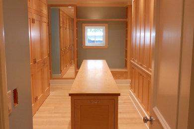 Example of a large classic gender-neutral light wood floor and beige floor dressing room design in Bridgeport with flat-panel cabinets and light wood cabinets