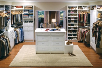 Diseño de armario vestidor unisex clásico grande con armarios con paneles con relieve, puertas de armario blancas, suelo de madera en tonos medios y suelo marrón