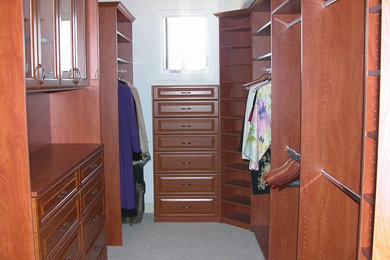 Diseño de armario vestidor unisex tradicional grande con armarios con paneles con relieve, puertas de armario de madera en tonos medios, moqueta y suelo gris