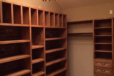 Large mountain style carpeted walk-in closet photo in Houston with light wood cabinets