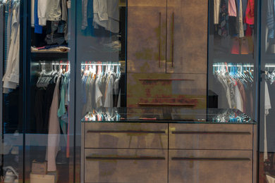 Large minimalist gender-neutral walk-in closet photo in Miami with glass-front cabinets and brown cabinets