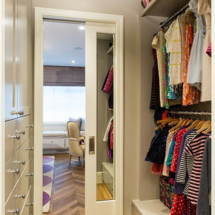 Example of a small trendy women's medium tone wood floor walk-in closet design in New York with gray cabinets