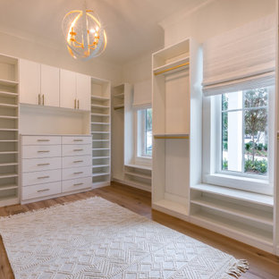 Diseño de armario vestidor de mujer, de estilo de casa de campo, de tamaño medio, con armarios estilo shaker, puertas de armario blancas, suelo de madera en tonos medios y suelo marrón