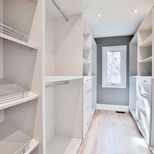 Imagen de armario vestidor de mujer, minimalista, grande, con armarios abiertos, puertas de armario blancas y suelo de madera clara