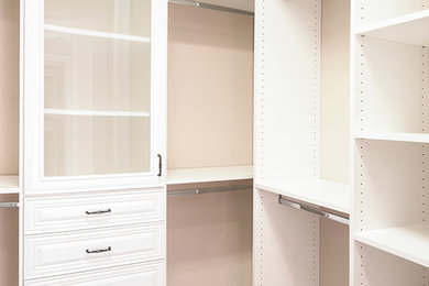Foto de armario vestidor unisex clásico de tamaño medio con armarios abiertos, puertas de armario blancas y suelo de madera oscura