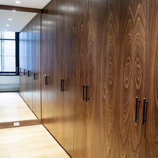 Immagine di una grande cabina armadio unisex industriale con ante lisce, ante in legno scuro, parquet chiaro e pavimento marrone