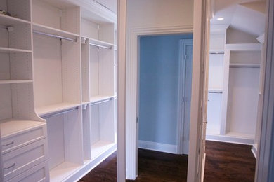 Imagen de armario vestidor unisex clásico grande con armarios estilo shaker, puertas de armario blancas, suelo de madera oscura y suelo marrón