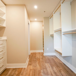 Idéer för att renovera ett mellanstort industriellt walk-in-closet för könsneutrala, med luckor med infälld panel, vita skåp, vinylgolv och brunt golv