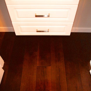 Imagen de armario unisex, moderno, pequeño, con armarios con paneles lisos, puertas de armario blancas y suelo de madera en tonos medios