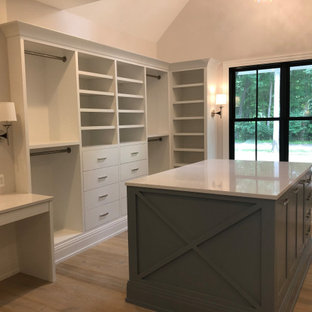 Esempio di una grande cabina armadio unisex con travi a vista, ante bianche e parquet chiaro