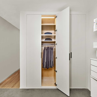Immagine di un armadio o armadio a muro unisex minimalista di medie dimensioni con ante lisce, ante bianche, pavimento in compensato e pavimento grigio