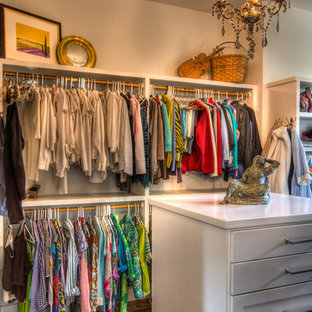 Ispirazione per una cabina armadio unisex boho chic di medie dimensioni con pavimento in legno massello medio, ante bianche e pavimento marrone