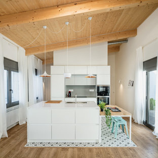 Ejemplo de cocina de galera, escandinava, abierta, con fregadero bajoencimera, armarios con paneles lisos, puertas de armario blancas, salpicadero verde, electrodomésticos negros, una isla, suelo multicolor y encimeras blancas