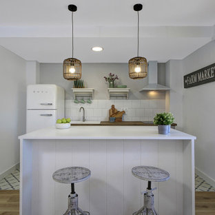 Foto de cocina de galera, campestre, pequeña, con fregadero encastrado, encimera de madera, salpicadero blanco, electrodomésticos blancos, una isla, suelo multicolor y encimeras marrones