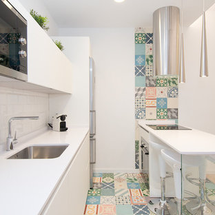Ejemplo de cocina escandinava con fregadero bajoencimera, salpicadero blanco, electrodomésticos de acero inoxidable, suelo multicolor, encimeras blancas, armarios con paneles lisos, puertas de armario blancas, salpicadero de azulejos tipo metro y península