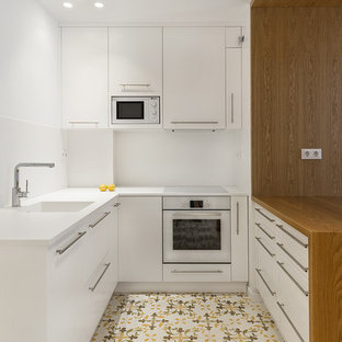 Foto de cocina en U, contemporánea, pequeña, con fregadero integrado, armarios con paneles lisos, puertas de armario blancas, salpicadero blanco, electrodomésticos blancos, suelo de baldosas de cerámica, península, suelo multicolor y encimeras blancas