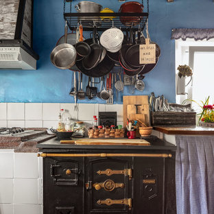 Ejemplo de cocina rústica, de tamaño medio, con encimera de madera, salpicadero blanco, salpicadero de azulejos de cerámica, encimeras marrones y electrodomésticos negros