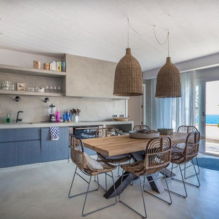Foto de cocina comedor en L, mediterránea, de tamaño medio, sin isla, con puertas de armario azules, encimera de cemento, salpicadero verde, suelo de cemento, suelo gris y armarios con paneles lisos