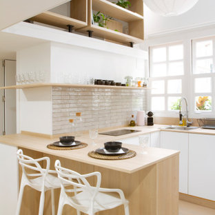 Design ideas for a scandinavian u-shaped kitchen in Madrid with a drop-in sink, flat-panel cabinets, white cabinets, wood benchtops, white splashback, light hardwood floors, a peninsula, beige floor and beige benchtop.