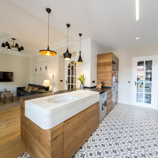 This is an example of a mid-sized contemporary galley open plan kitchen in Alicante-Costa Blanca with flat-panel cabinets, medium wood cabinets, white splashback, subway tile splashback, a peninsula, a farmhouse sink, marble benchtops, stainless steel appliances, terra-cotta floors and blue floor.