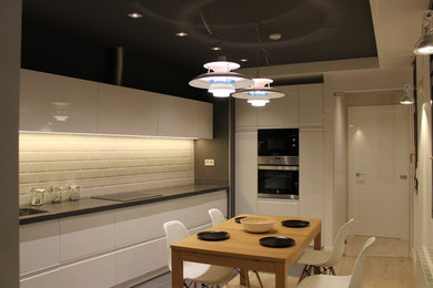 Bild på ett mellanstort funkis kök, med släta luckor, vita skåp, vitt stänkskydd och rostfria vitvaror