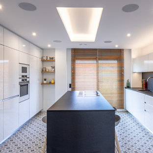 Foto de cocina escandinava, grande, con fregadero bajoencimera, armarios con paneles lisos, puertas de armario blancas, encimera de cuarzo compacto, salpicadero negro, electrodomésticos con paneles, suelo de azulejos de cemento, una isla, suelo multicolor y encimeras negras