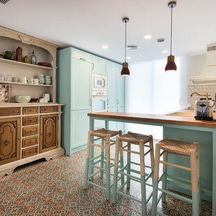 Foto de cocina en L, mediterránea, de tamaño medio, con puertas de armario turquesas, encimera de madera, suelo de baldosas de cerámica, península, fregadero encastrado, salpicadero blanco, suelo multicolor y encimeras beige