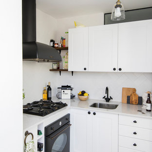 Imagen de cocina en L, escandinava, pequeña, sin isla, con fregadero bajoencimera, armarios estilo shaker, puertas de armario blancas, encimera de mármol, salpicadero blanco, salpicadero de azulejos de cerámica, electrodomésticos negros, suelo de baldosas de cerámica y encimeras blancas