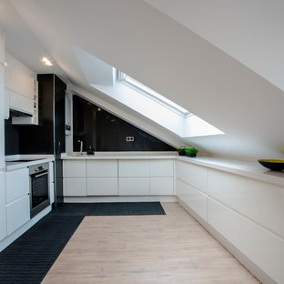 Imagen de cocina en U, contemporánea, sin isla, con armarios con paneles lisos, puertas de armario blancas, salpicadero negro y encimeras blancas