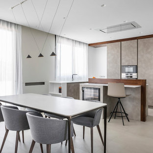 Imagen de cocina comedor en L, minimalista, con armarios con paneles lisos, puertas de armario beige, suelo beige, encimeras blancas y dos o más islas