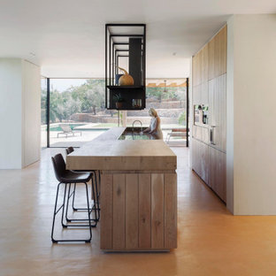 Foto de cocina mediterránea con puertas de armario de madera clara, encimera de madera, una isla y suelo beige
