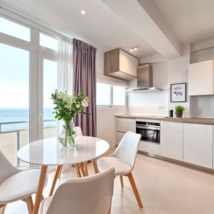 Modelo de cocina comedor en L, nórdica, pequeña, sin isla, con fregadero de un seno, armarios con paneles lisos, puertas de armario blancas, salpicadero blanco, electrodomésticos de acero inoxidable y suelo de baldosas de cerámica