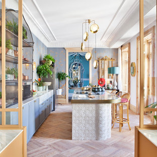 Ejemplo de cocina de galera, bohemia, con fregadero bajoencimera, armarios con paneles con relieve, puertas de armario azules, electrodomésticos de acero inoxidable, una isla, suelo beige y encimeras blancas