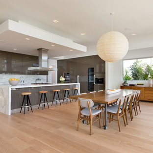 Foto de cocina en L, actual, abierta, con armarios con paneles lisos, salpicadero blanco, suelo de madera clara, encimeras blancas, puertas de armario grises, una isla y suelo beige