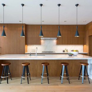 Foto de cocina contemporánea, grande, con fregadero bajoencimera, armarios con paneles lisos, puertas de armario de madera oscura, encimera de cuarzo compacto, salpicadero blanco, suelo de madera en tonos medios, una isla, encimeras blancas y suelo marrón
