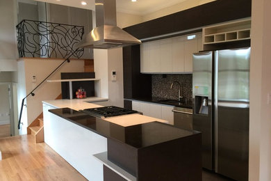 Moderne Küche mit Unterbauwaschbecken, flächenbündigen Schrankfronten, weißen Schränken, Quarzwerkstein-Arbeitsplatte, Küchenrückwand in Grau, Küchengeräten aus Edelstahl, braunem Holzboden und Kücheninsel in Miami
